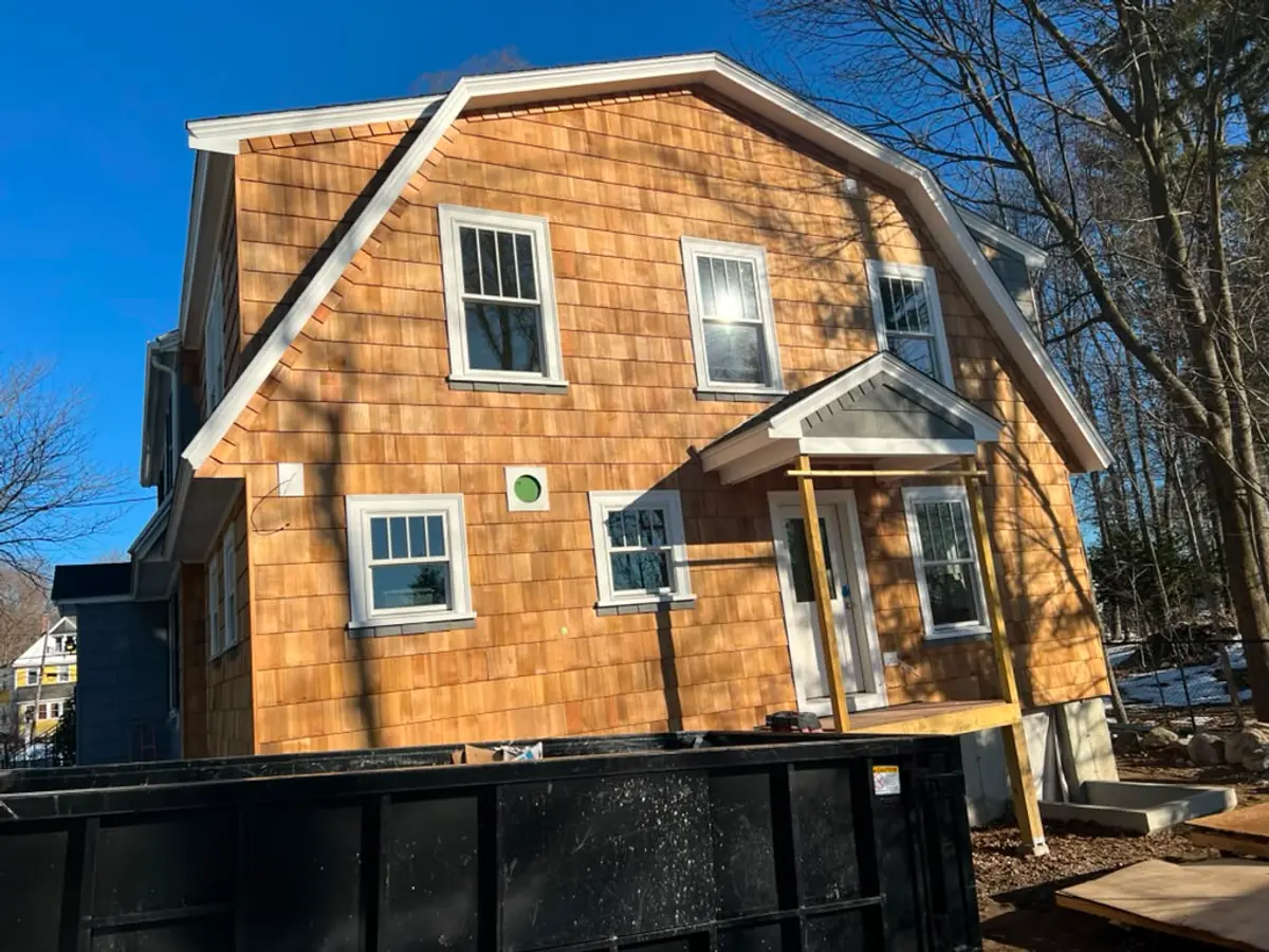 Close detail of hand-coursed western red cedar shingles and white window trim in Reading, MA