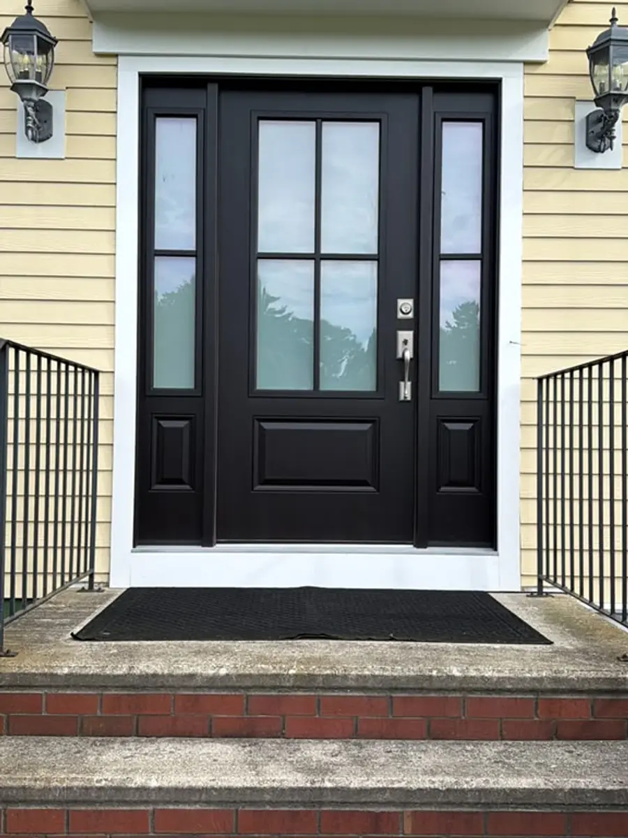 Black fiberglass entry door with sidelights installed in Norfolk, MA against yellow clapboard