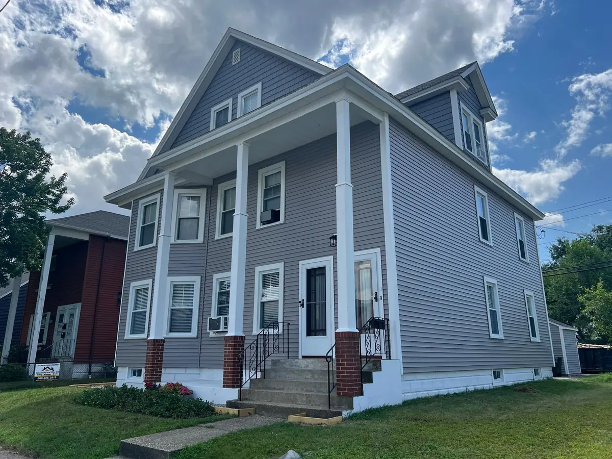 Finished front of a Manchester, NH two-family with new grey vinyl siding and white porch columns