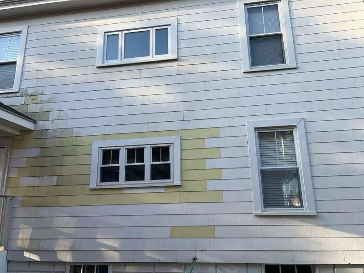 Old cement-shingle siding in Manchester, NH with mismatched patches and weather staining