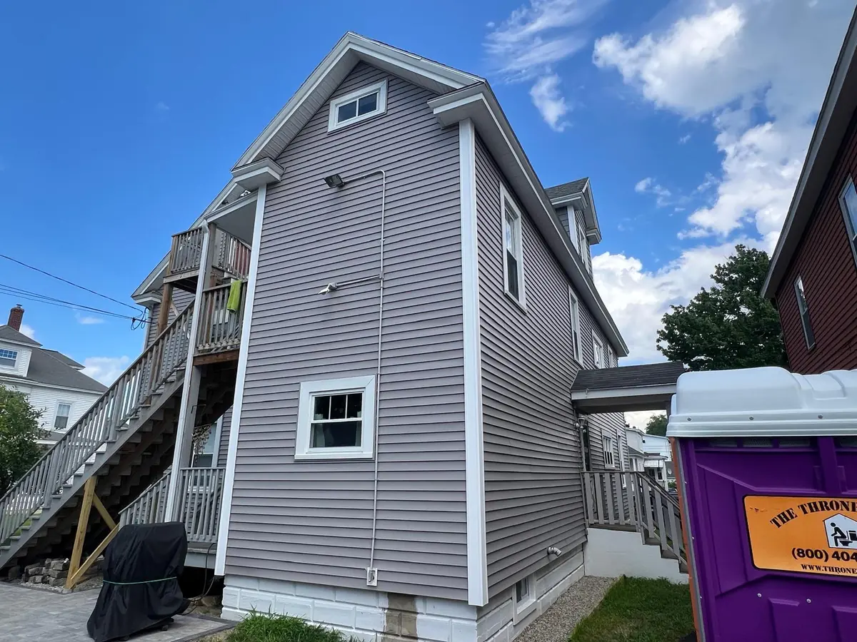 Gable end of a Manchester, NH two-family after residing, with a shingled dormer