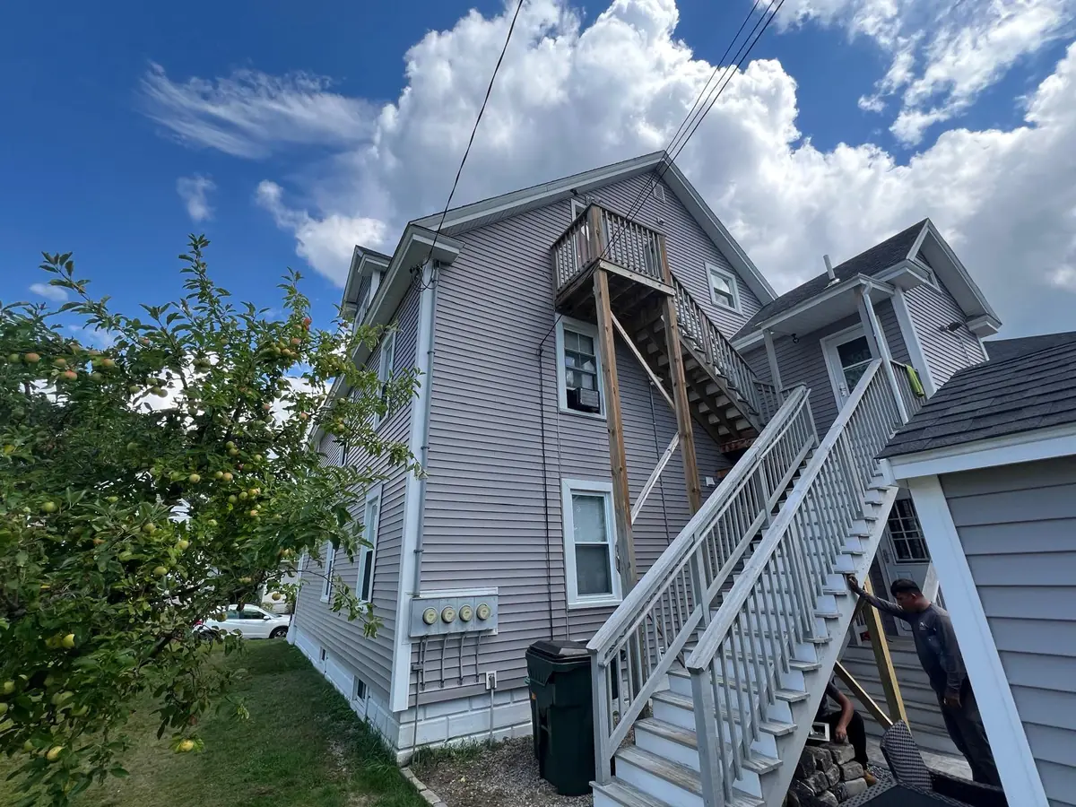 Staircase side of a Manchester, NH two-family finished in grey vinyl siding