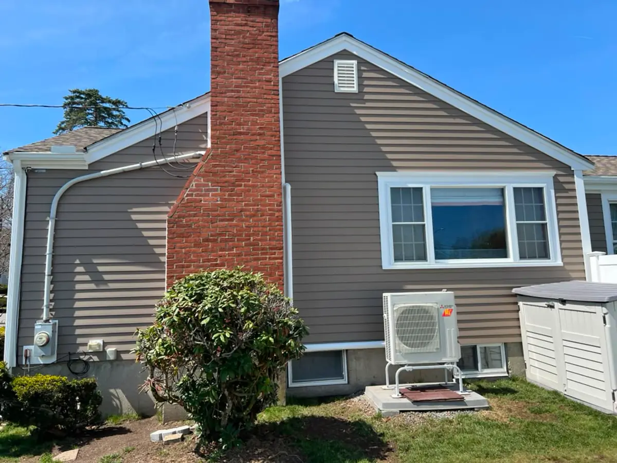Rear elevation in Woburn, MA where new siding meets the original brick chimney