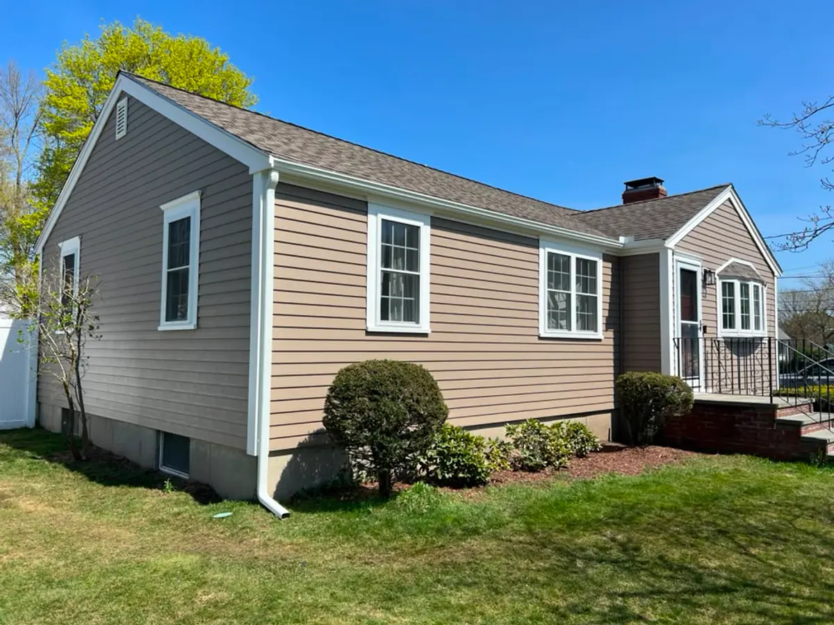 Gable end of a Woburn, MA ranch after residing, with new downspout and white rake trim